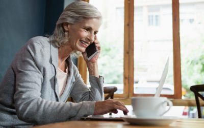 pikwizard smiling senior woman talking on mobile phone while working on laptop